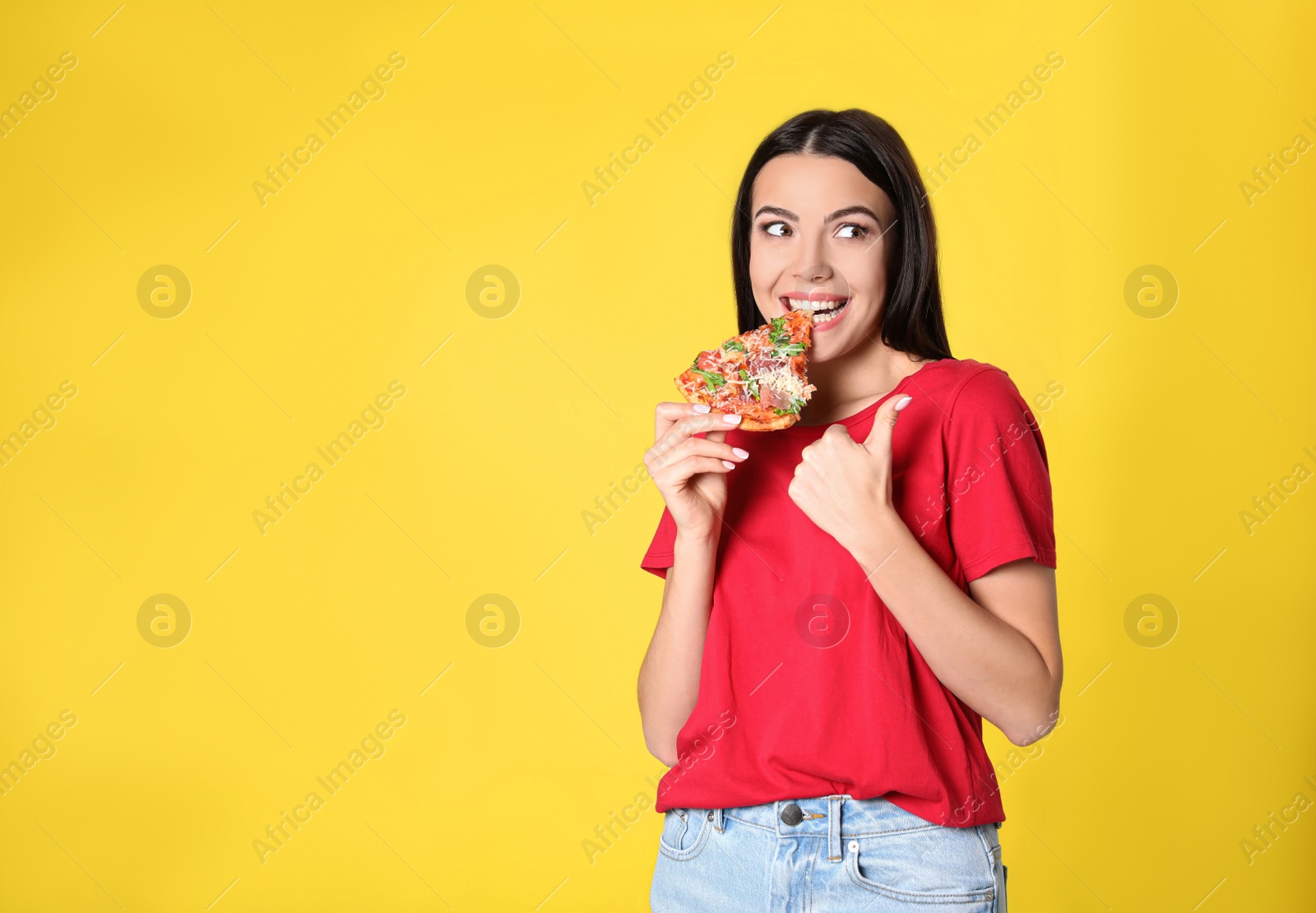 Photo of Emotional woman eating tasty pizza on yellow background