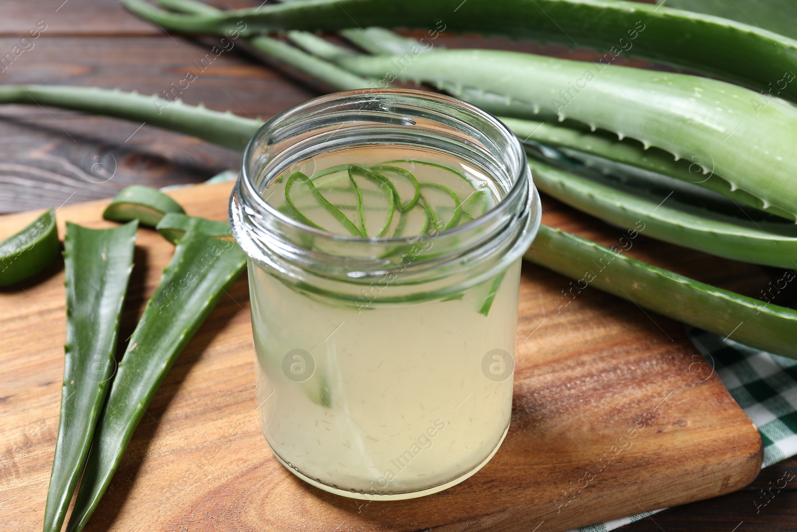 Photo of Fresh aloe juice in jar and leaves on wooden table, closeup