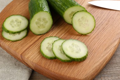 Photo of Cucumbers. knife and cutting board on table, closeup
