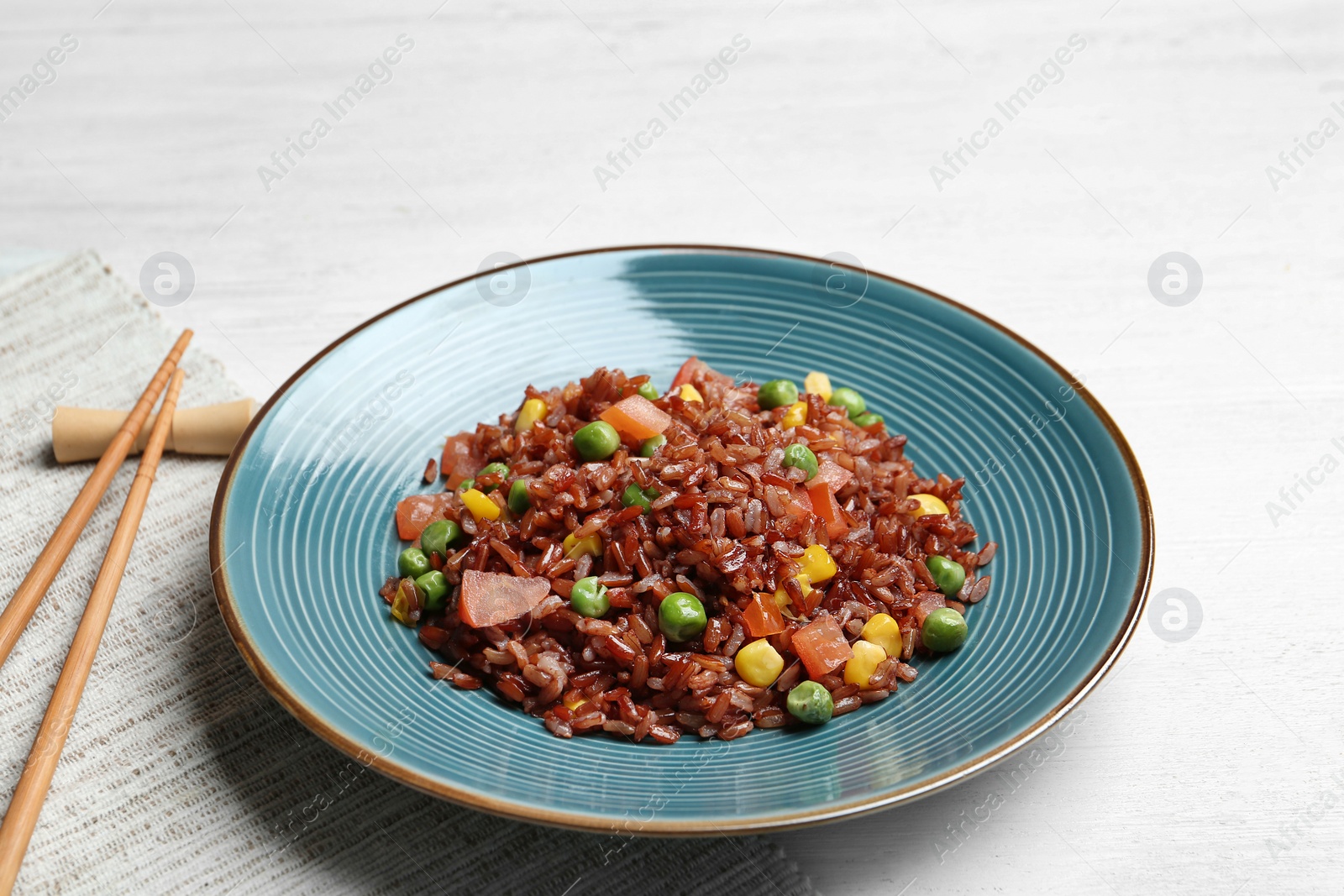 Photo of Plate of boiled brown rice with vegetables served on table