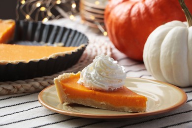 Photo of Piece of fresh homemade pumpkin pie with whipped cream on table
