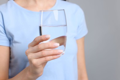 Photo of Healthy habit. Closeup of woman holding glass with fresh water on grey background