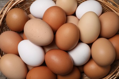 Photo of Fresh chicken eggs in wicker basket, top view