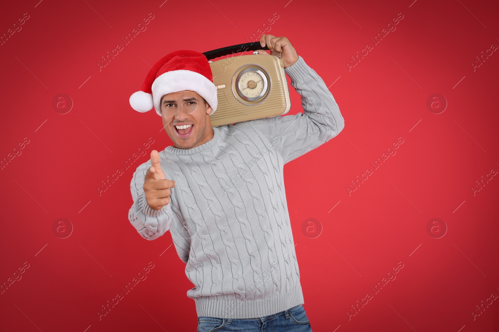 Photo of Emotional man with vintage radio on red background. Christmas music