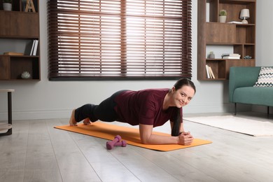 Photo of Overweight woman doing plank exercise at home