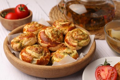 Fresh delicious puff pastry with tasty filling and tomatoes on white wooden table, closeup