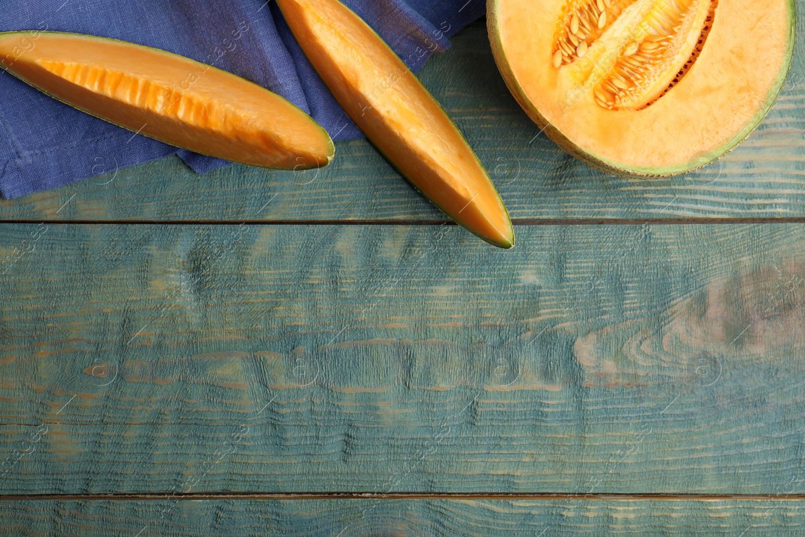 Photo of Tasty fresh cut melon on light blue wooden table, flat lay. Space for text