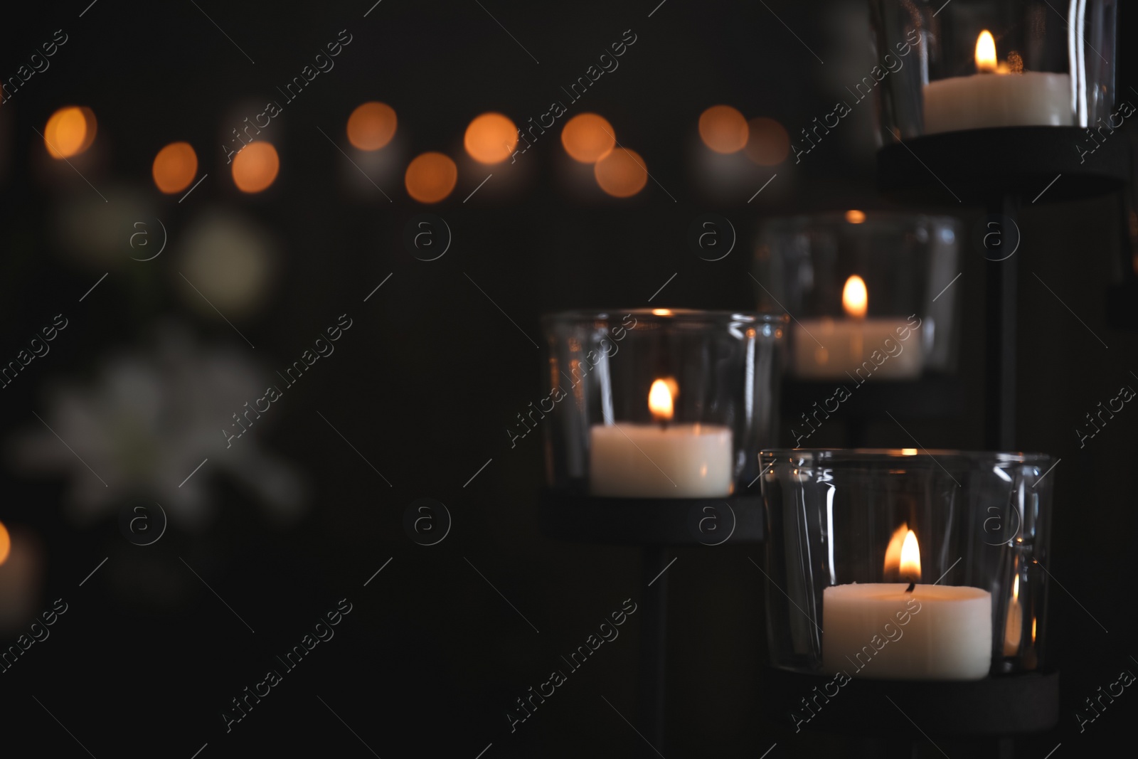 Photo of Burning candles on blurred background, space for text. Funeral symbol