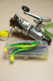 Photo of Different fishing baits and reel with line on light wooden table