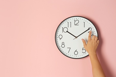 Woman touching clock on color wall, space for text. Time management