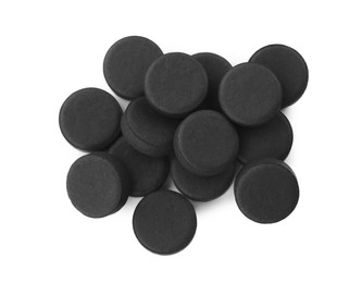 Photo of Activated charcoal pills on white background, top view. Potent sorbent