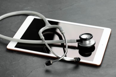 Photo of Modern tablet and stethoscope on black table