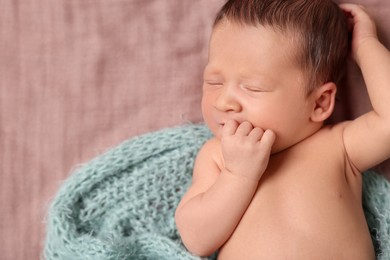 Photo of Adorable newborn baby in turquoise knitted blanket sleeping on bed. Space for text