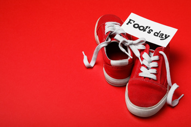 Shoes tied together and note with phrase FOOL'S DAY on red background. Space for text