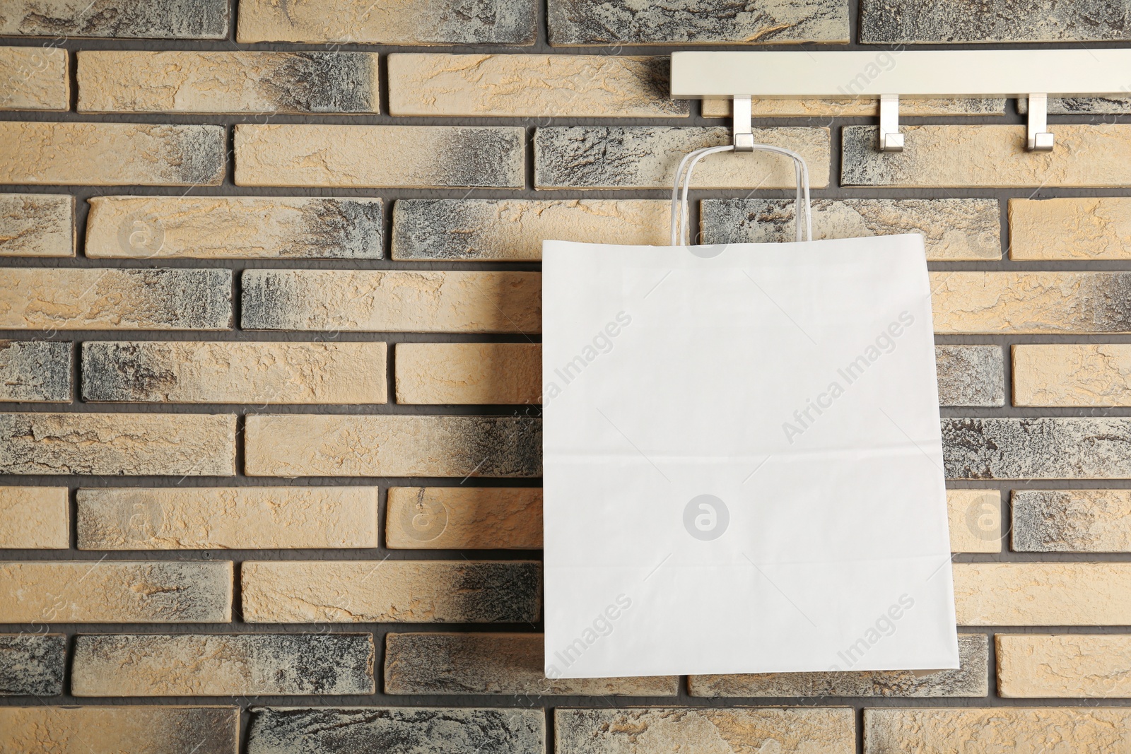 Photo of Rack with paper shopping bag on brick wall