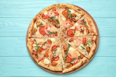 Photo of Delicious seafood pizza on light blue wooden table, top view