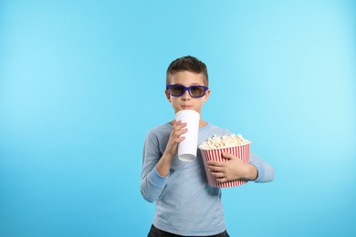 Photo of Boy with 3D glasses, popcorn and beverage during cinema show on color background