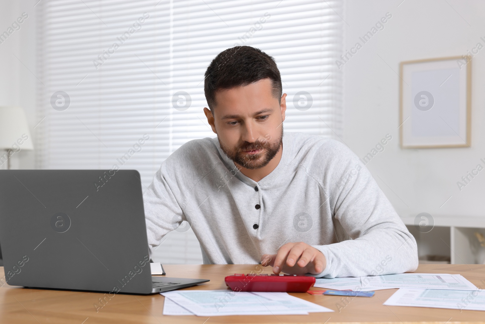 Photo of Man calculating taxes at table in room