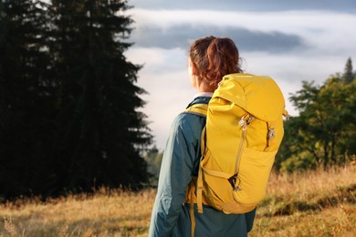 Photo of Tourist with backpack in nature on sunny day, back view. Space for text