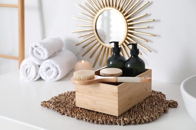 Photo of Wooden box with different toiletries and brush on countertop in bathroom