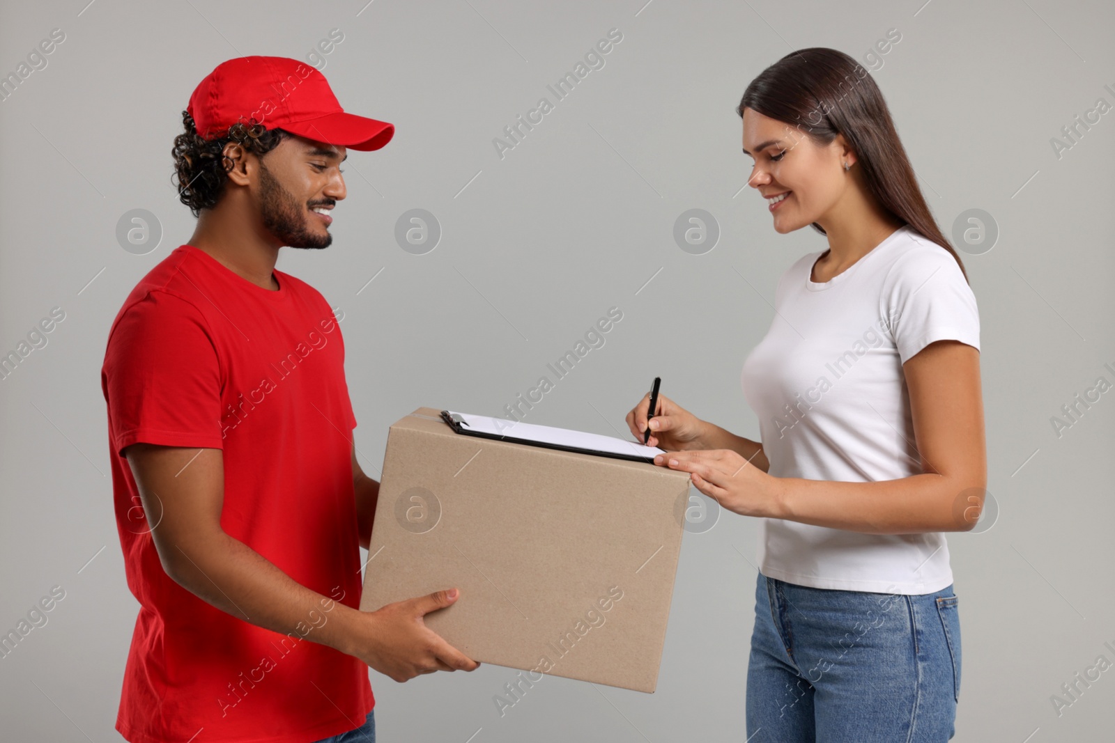 Photo of Smiling woman signing order receipt on grey background. Courier delivery