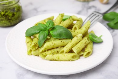 Photo of Delicious pasta with pesto sauce and basil on white marble table, closeup