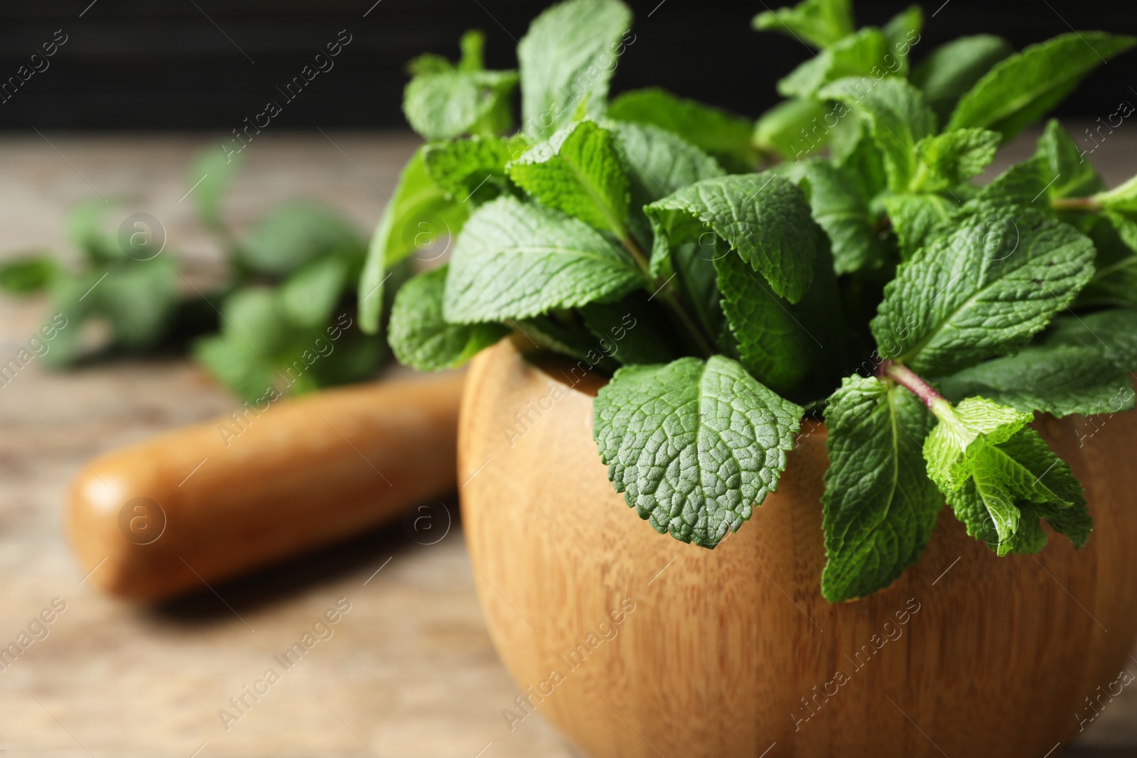 Photo of Wooden mortar with fresh green mint on table, closeup. Space for text