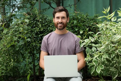 Photo of Handsome man with laptop in green garden