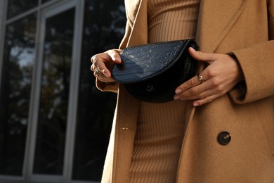 Photo of Young woman with stylish waist bag outdoors, closeup