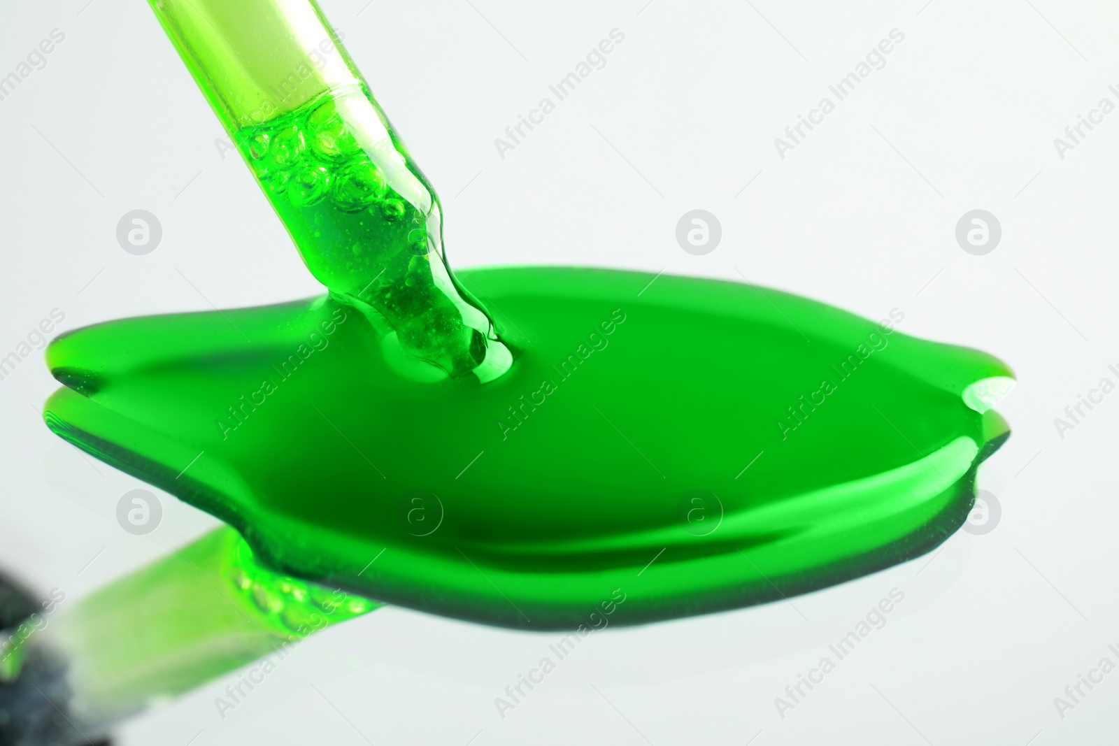 Photo of Dripping green serum from pipette on mirror, closeup