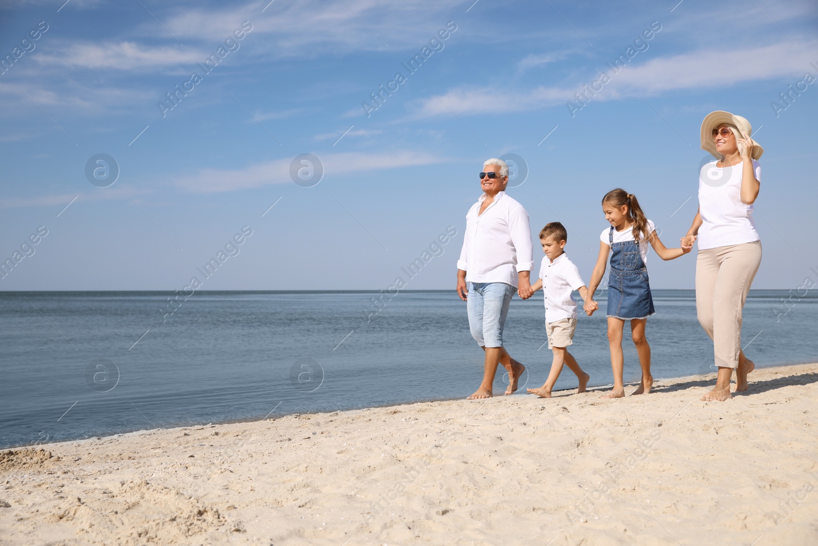 Photo of Cute little children with grandparents spending time together on sea beach