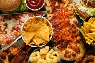 Onion rings, pizza and other fast food as background, top view