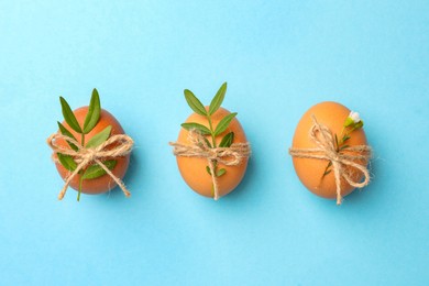 Chicken eggs and natural decor on light blue background, flat lay. Happy Easter