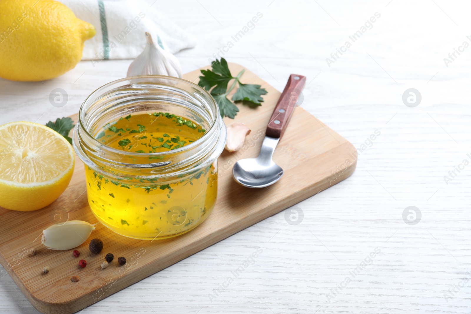 Photo of Jar with lemon sauce and ingredients on white wooden table, space for text. Delicious salad dressing