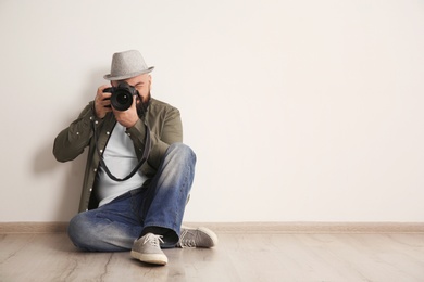 Male photographer with camera near light wall