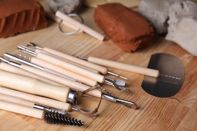 Clay and set of modeling tools on wooden table, closeup