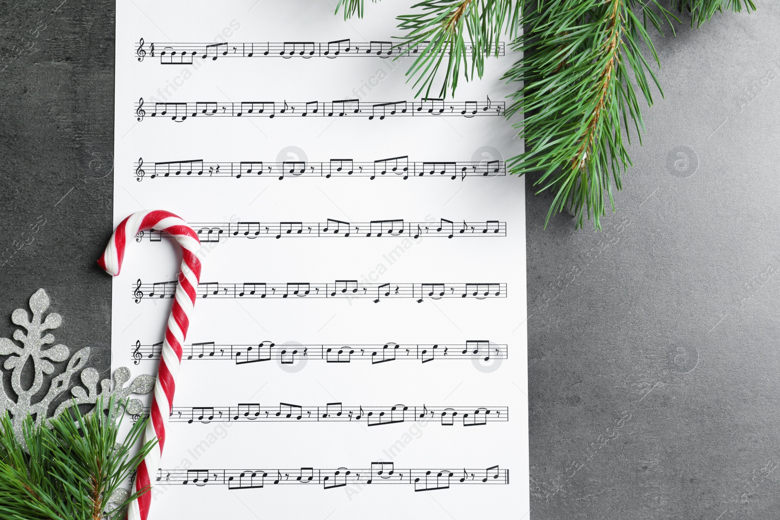 Photo of Flat lay composition with candy cane, fir branches and music sheet on table. Christmas songs concept