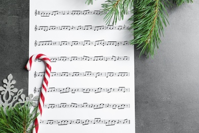Photo of Flat lay composition with candy cane, fir branches and music sheet on table. Christmas songs concept