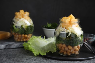 Photo of Healthy salad in glass jars on grey table