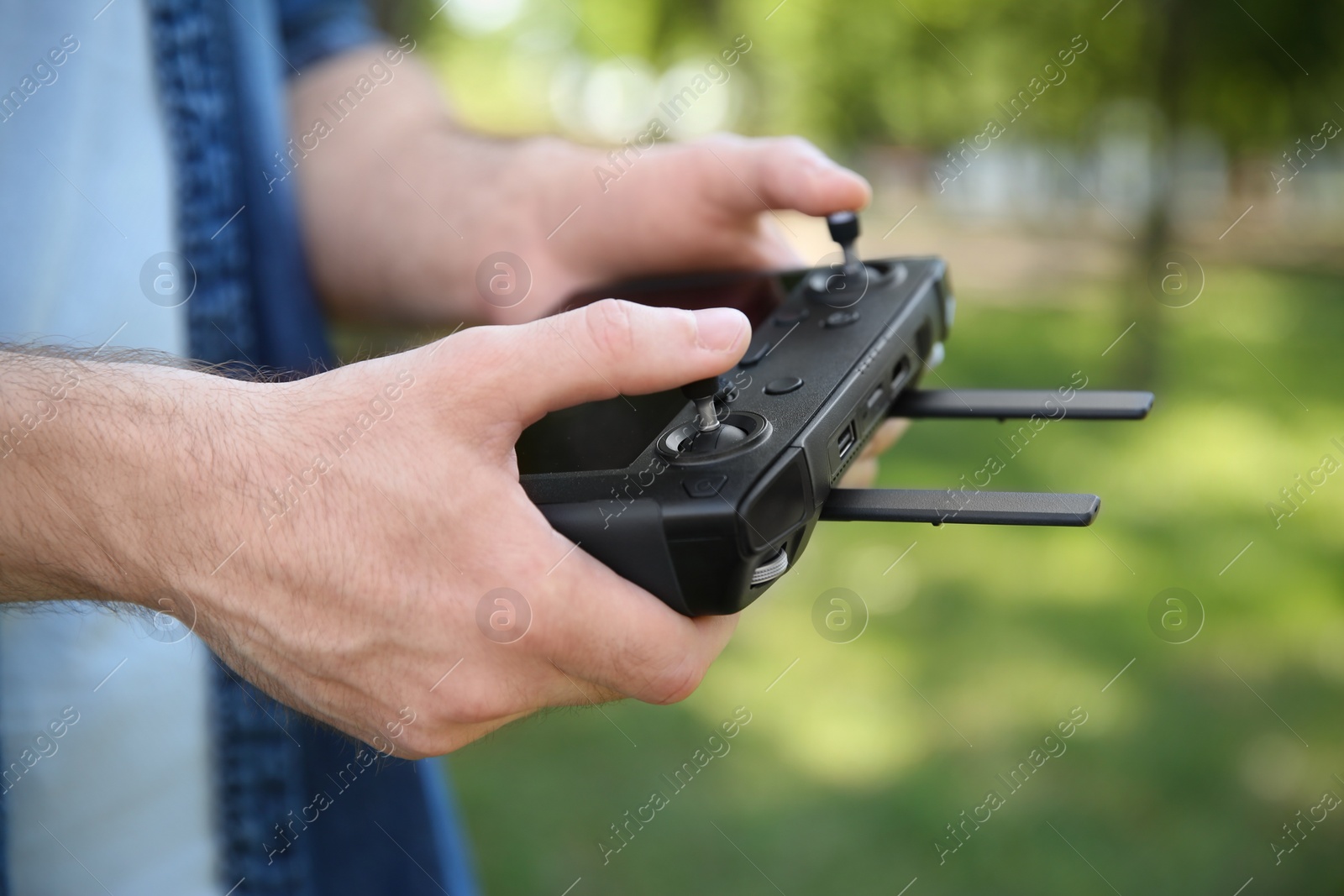 Photo of Man holding new modern drone controller outdoors, closeup of hands