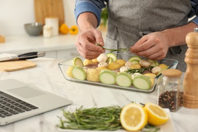 Photo of Man making dinner while watching online cooking course via laptop kitchen, closeup