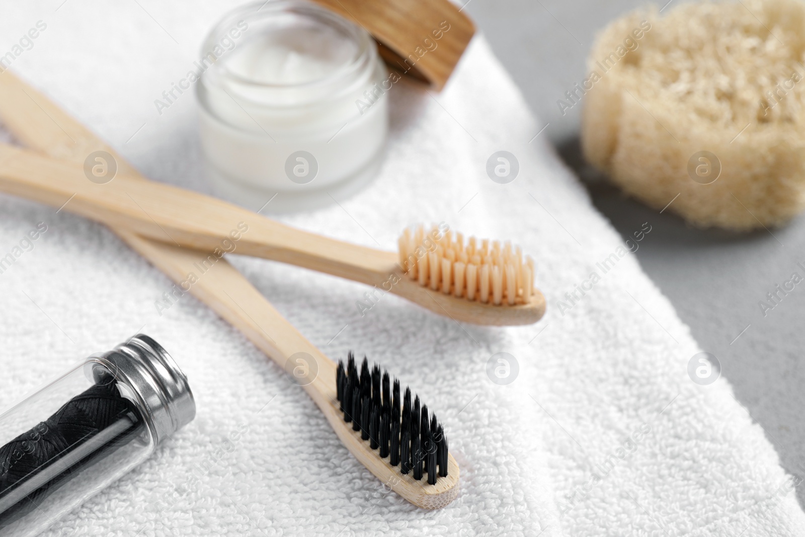 Photo of Bamboo toothbrushes, natural dental floss and towel on table, closeup