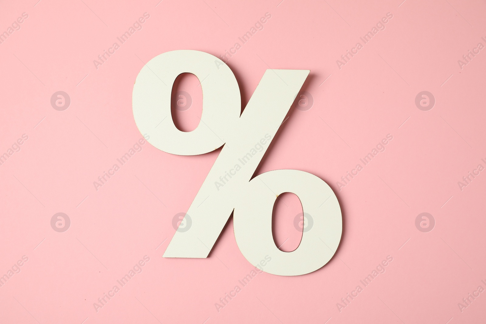 Photo of White percent sign on pink background, top view