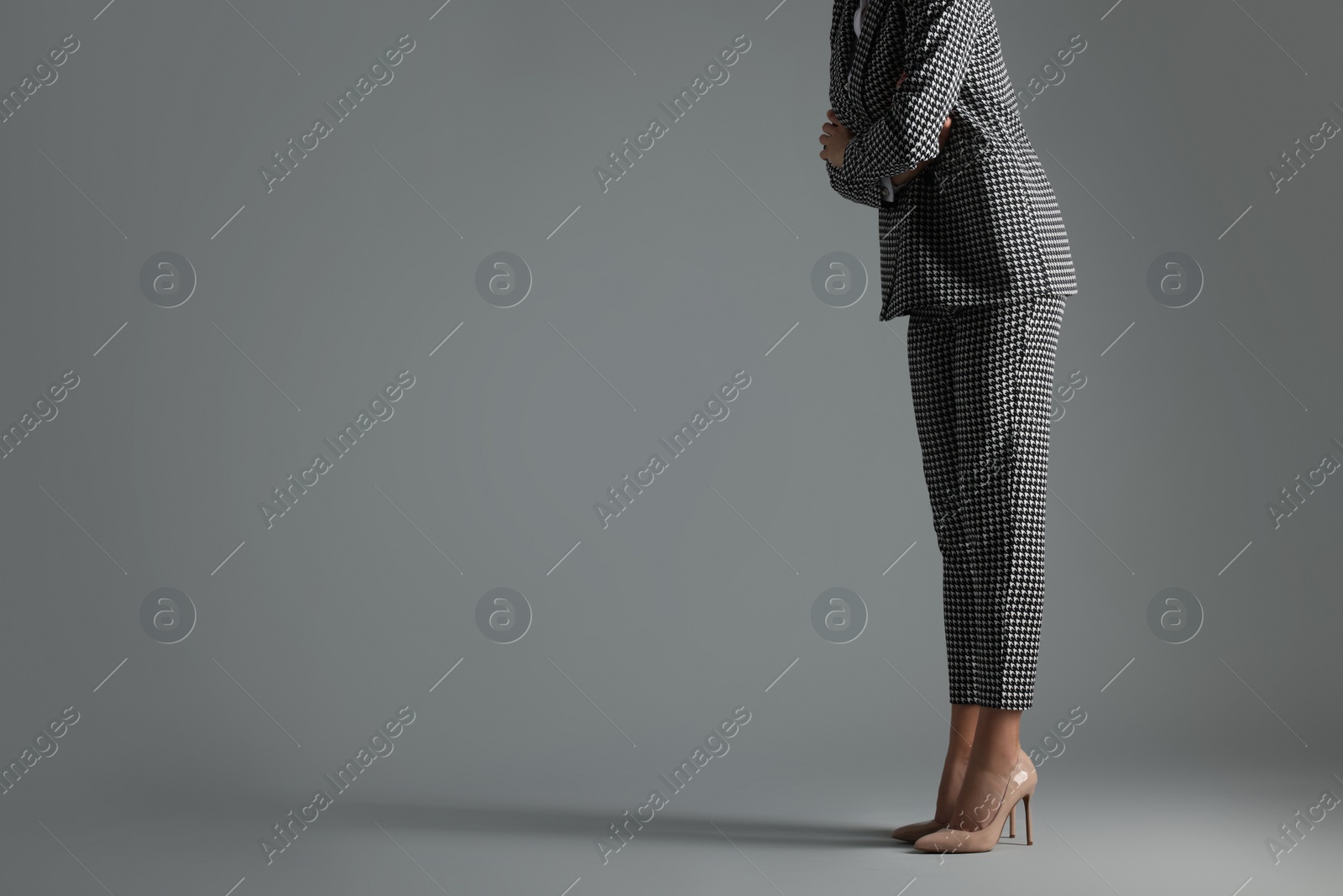 Photo of Businesswoman in beige shoes on grey background, closeup. Space for text