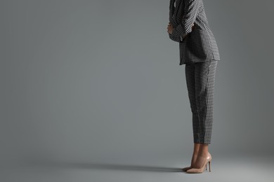 Businesswoman in beige shoes on grey background, closeup. Space for text