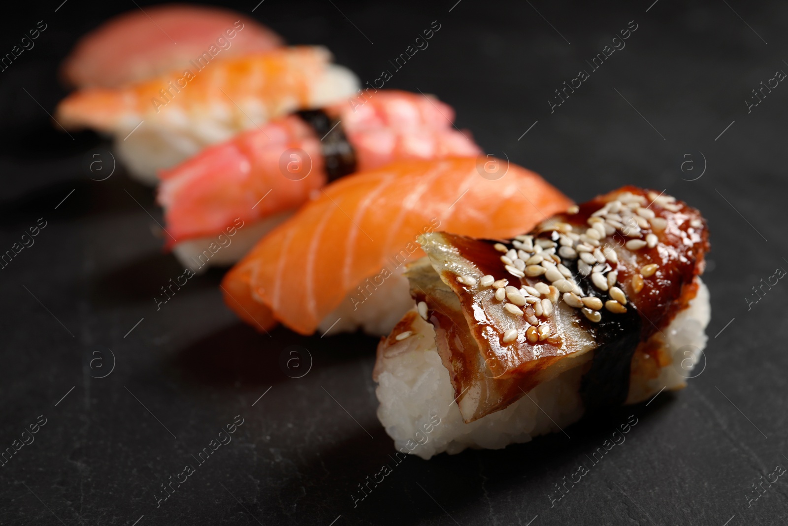 Photo of Delicious nigiri sushi on black table, closeup. Traditional Japanese cuisine