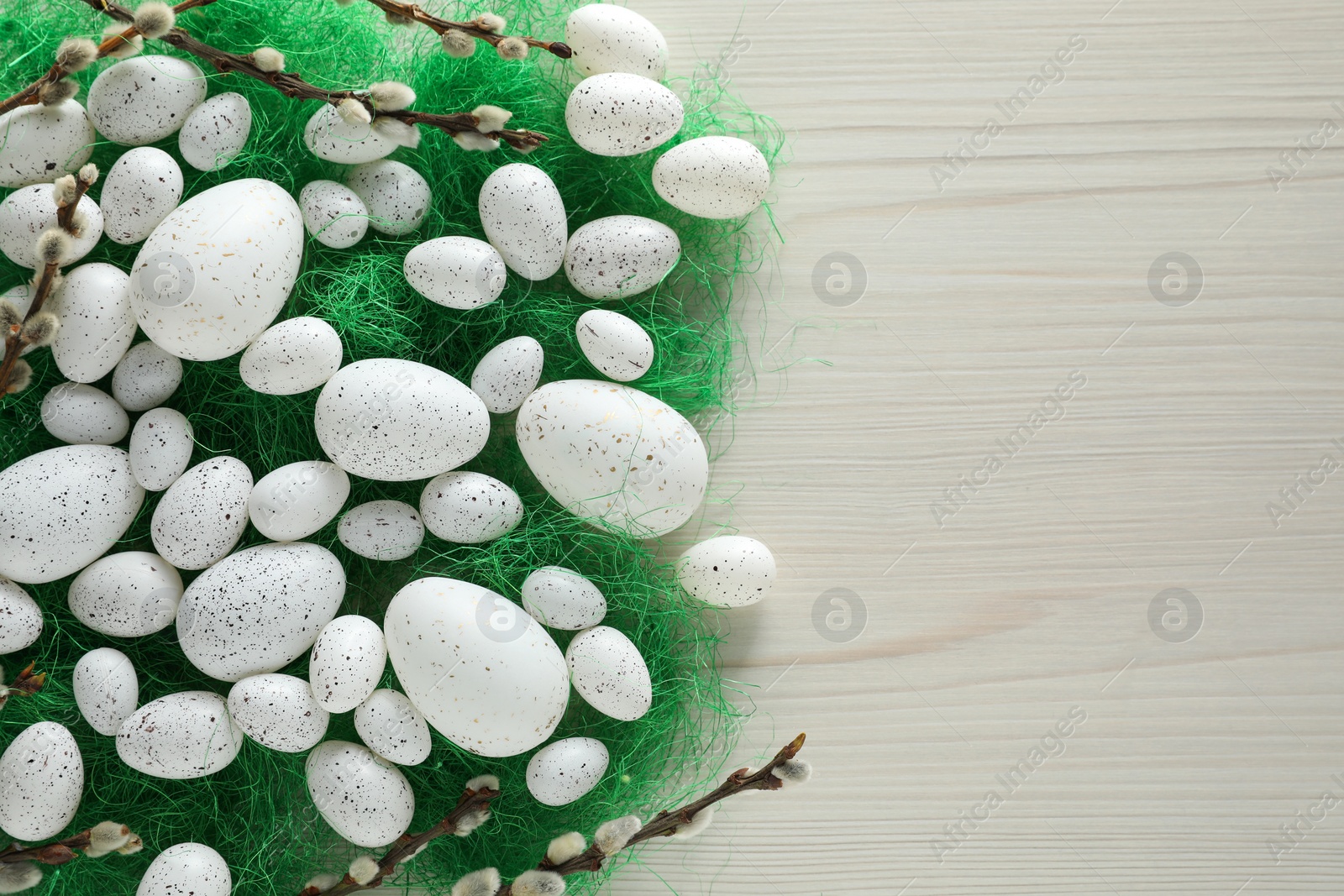 Photo of Many beautifully painted Easter eggs and pussy willow branches on white wooden table, flat lay. Space for text