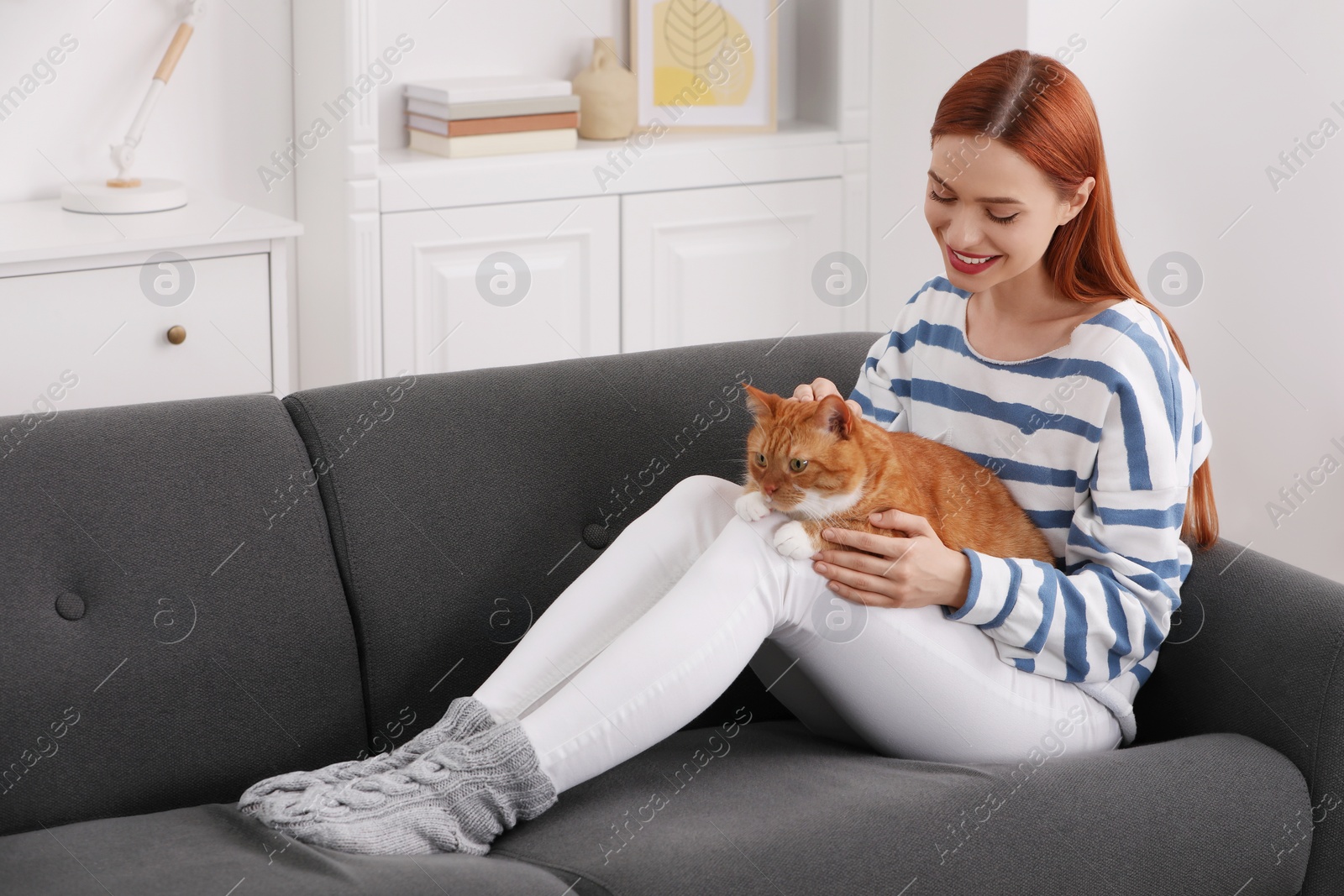 Photo of Happy woman with her cute cat on sofa at home