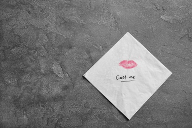 Photo of Paper napkin with lipstick mark and words CALL ME on grey background, top view. Space for text