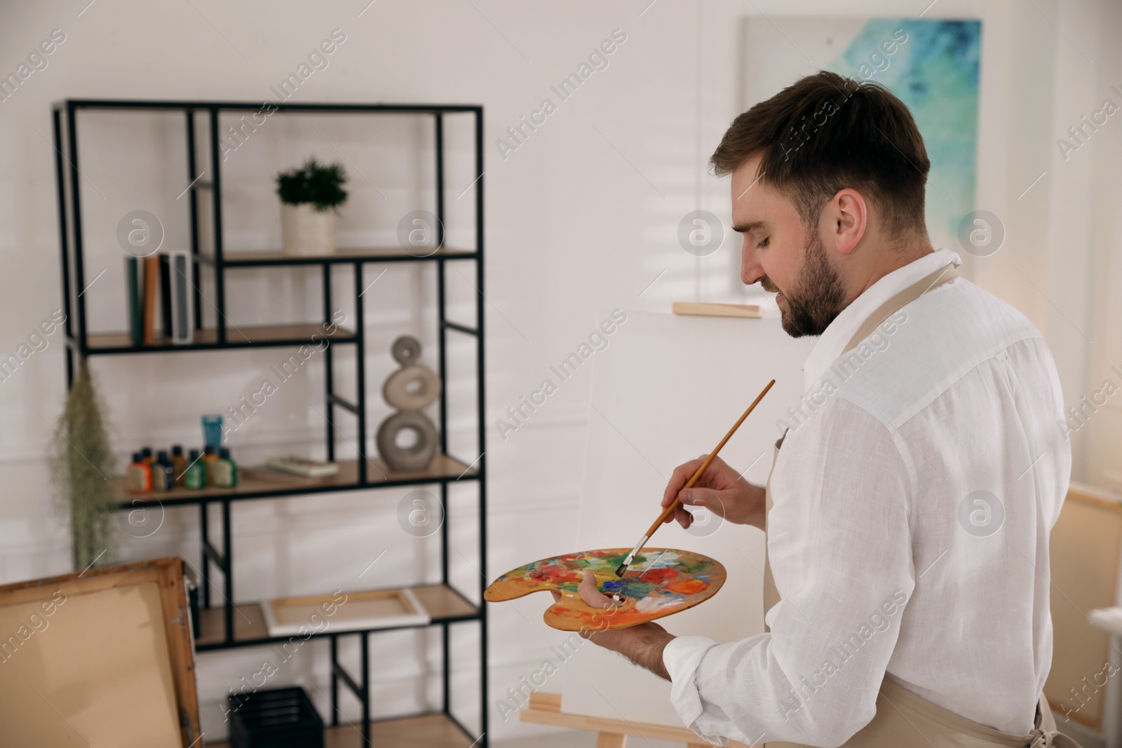 Photo of Young man painting with brush in artist studio